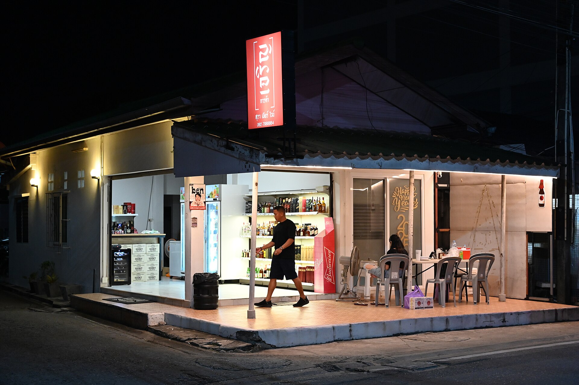 Small corner shop glowing under a red sign at night