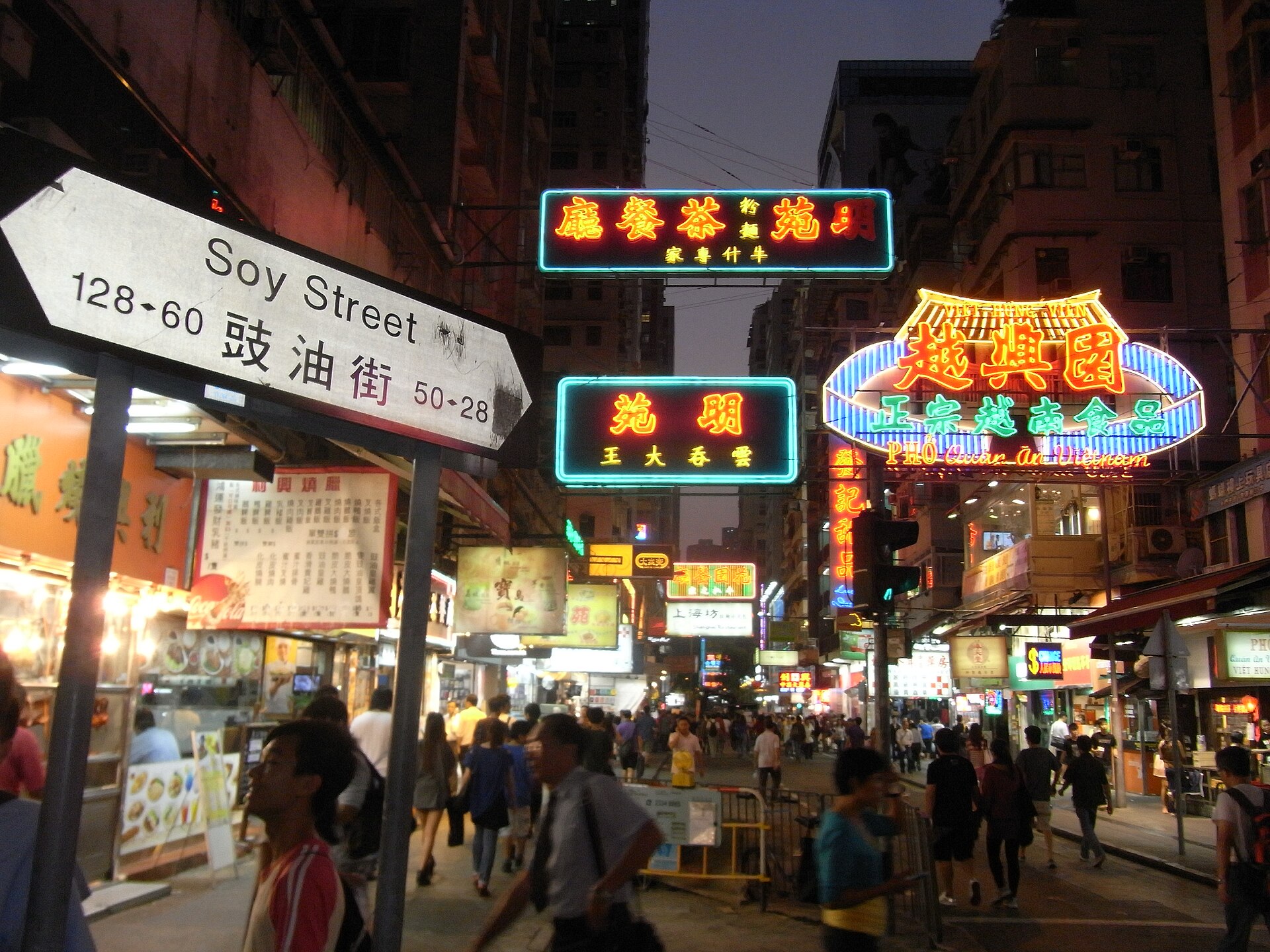 Dense wall of glowing shop signs on a Hong Kong street at night